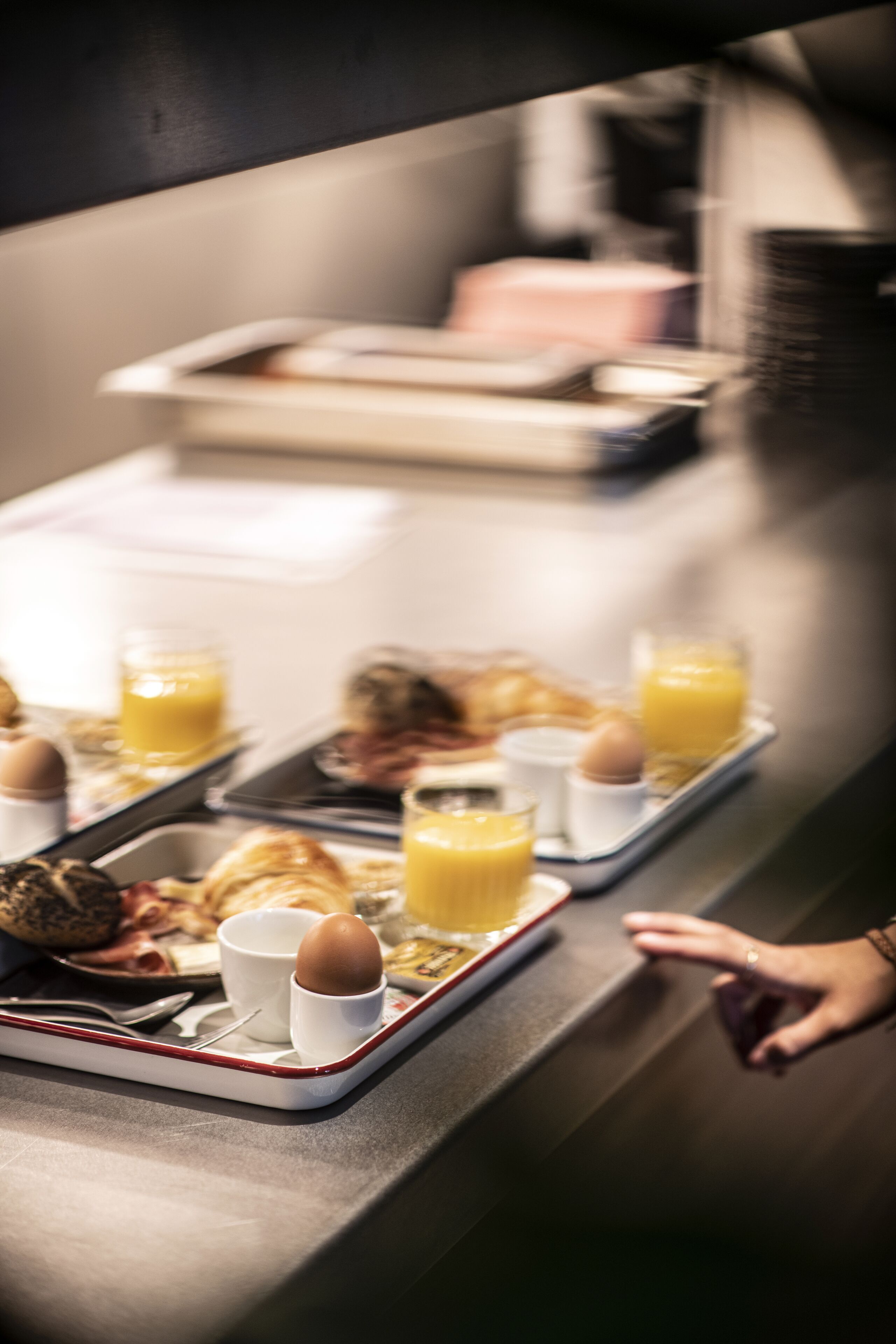 A breakfast tray with eggs, toast, and orange juice on a stainless steel counter.