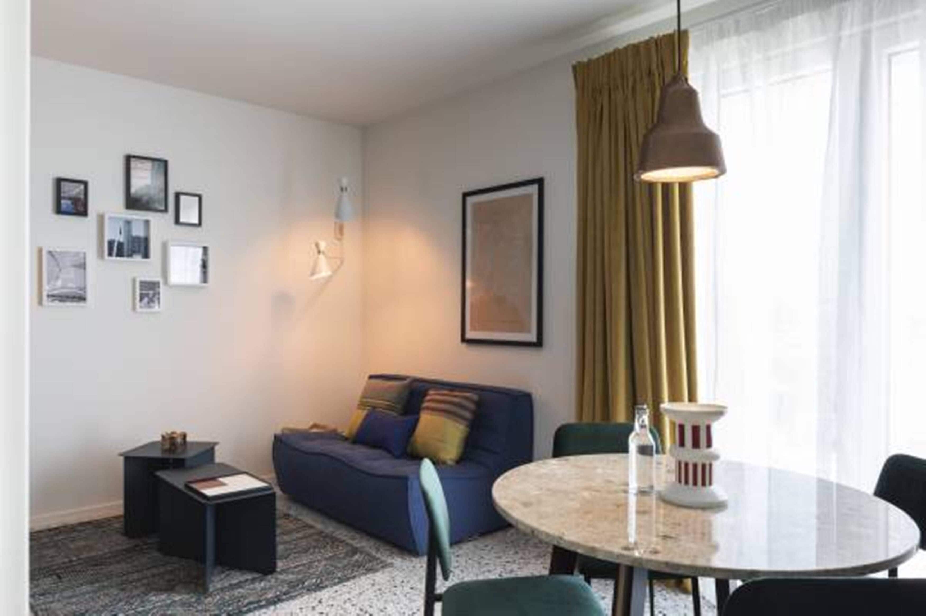Un salon moderne avec un canapé, une table ronde et une lampe.