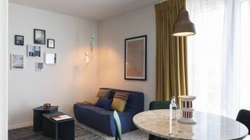 A modern living room with a sofa, a round table, and a lamp.