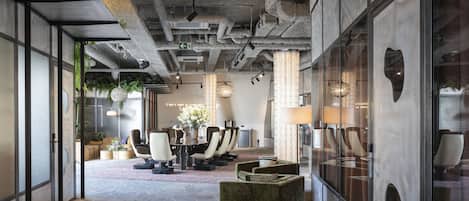 A modern conference room with a stone floor, leather chairs, and a glass partition.