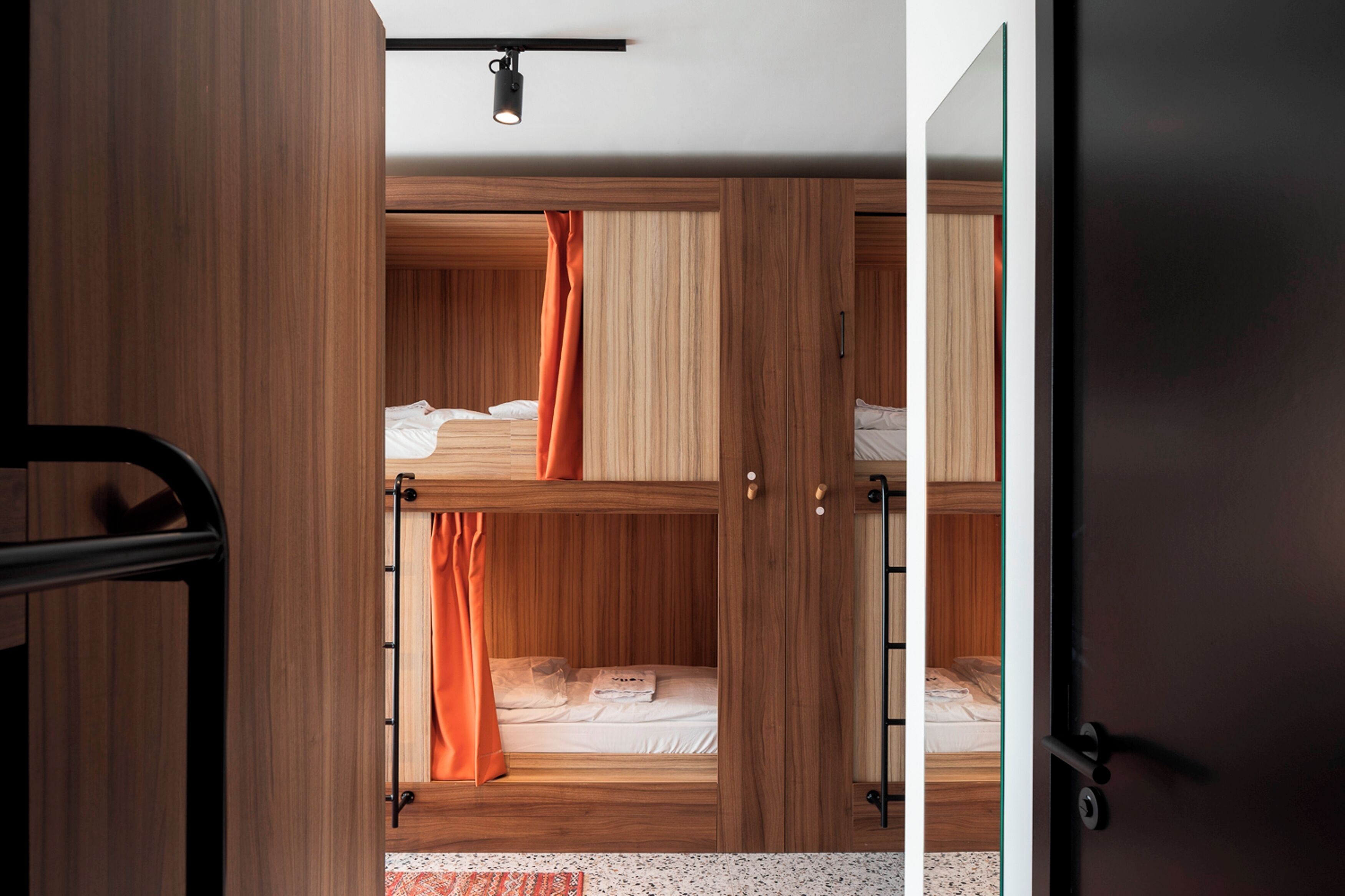 Quarto com beliche, paredes de madeira e uma porta.
