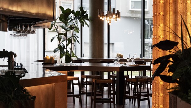 A modern restaurant interior with a central column, hanging lights, and a view of the city through large windows. - YUST Liège (Liege)