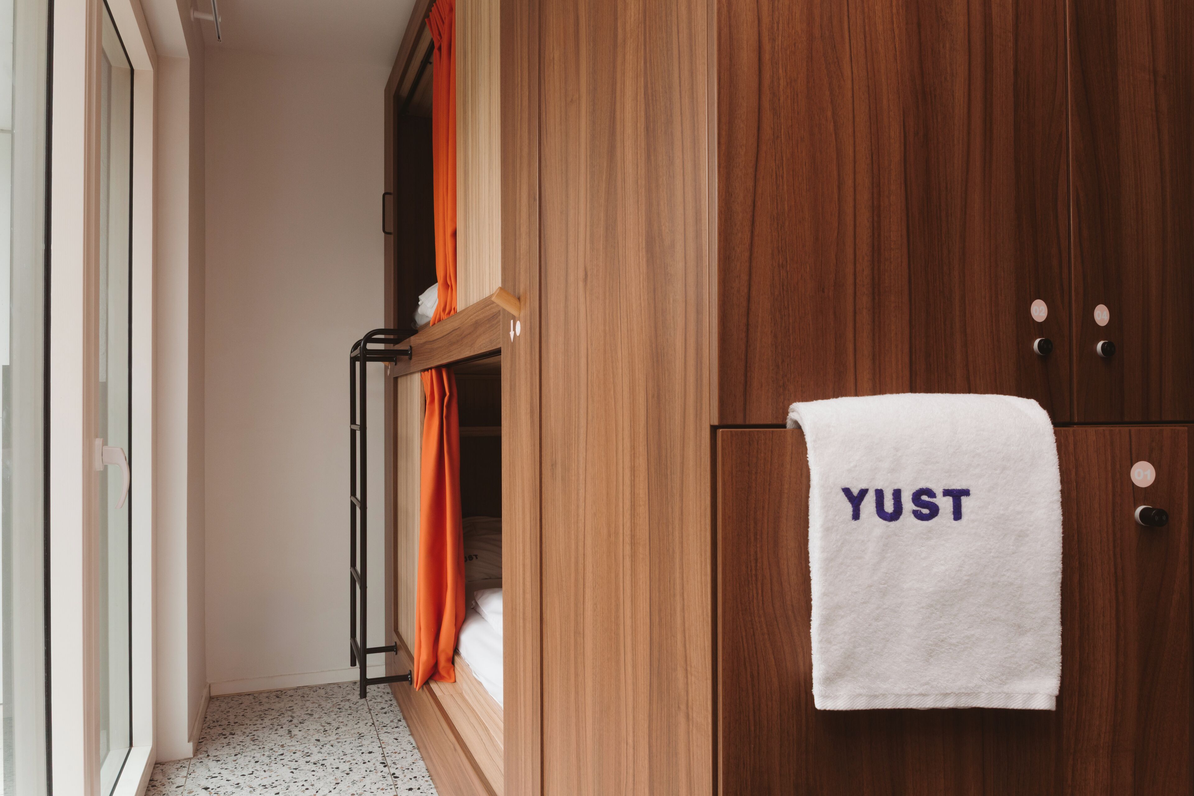 A wooden wardrobe with a white towel hanging on it that reads "YUST".