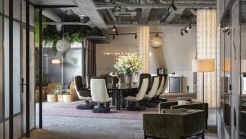 A modern meeting room with a glass partition, a round table, and comfortable seating.