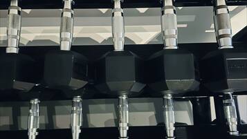 A rack of black dumbbells with weight markings, including 20KG, arranged in a gym setting.