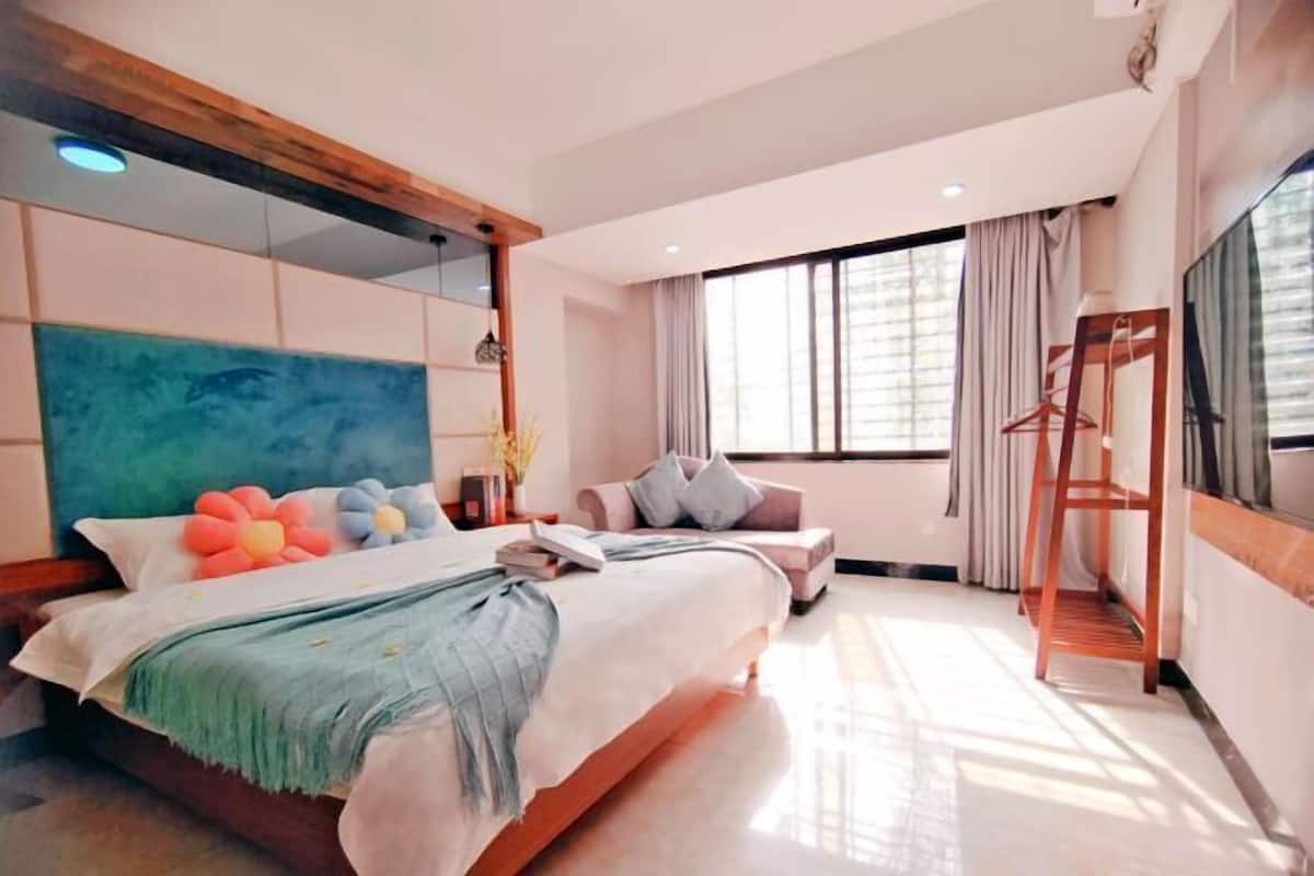 A modern bedroom with a large bed, a seating area, and a TV.