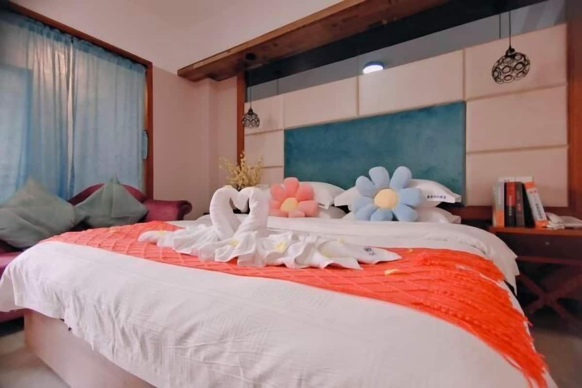 A neatly made bed with a white and orange bedspread, decorative swan pillows, and a blue and white headboard.