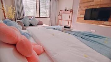 A modern bedroom with a bed, a large plush toy, a desk, and a TV mounted on a wooden wall.