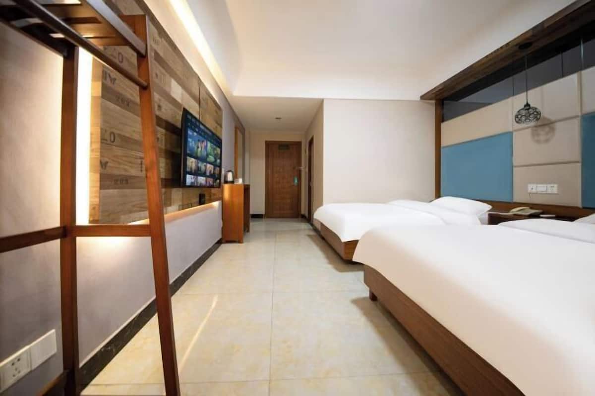 A hotel room with a large bed, a desk with a computer, and a television on the wall.