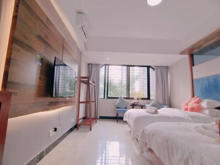 Una habitació d'hotel amb dos llits, televisió, finestra amb cortines i un mur de destaca de fusta.