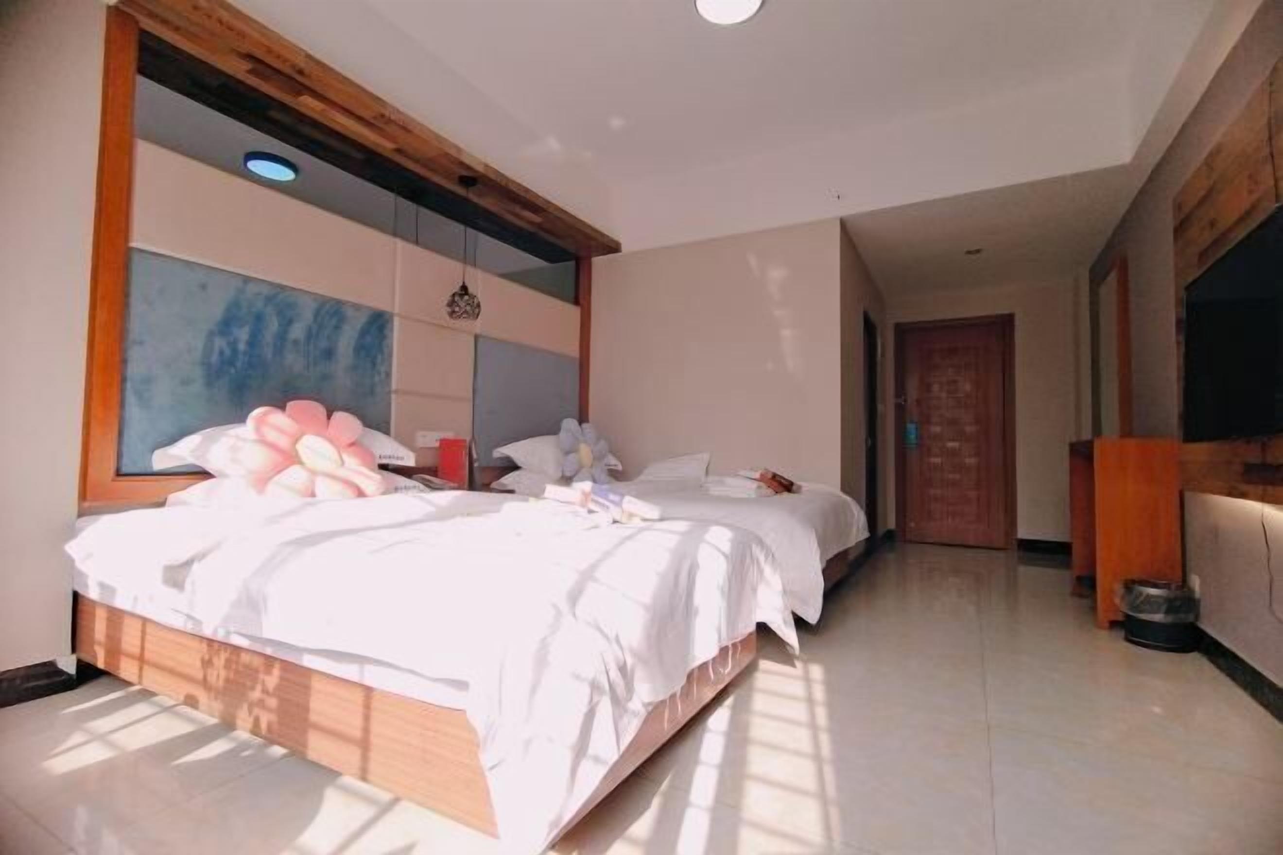 A bedroom with two beds, a large window, and a wooden ceiling.