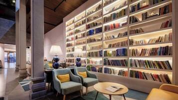 A modern library with bookshelves, seating, and a lamp.