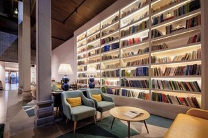 A modern library with bookshelves, seating, and a lamp.
