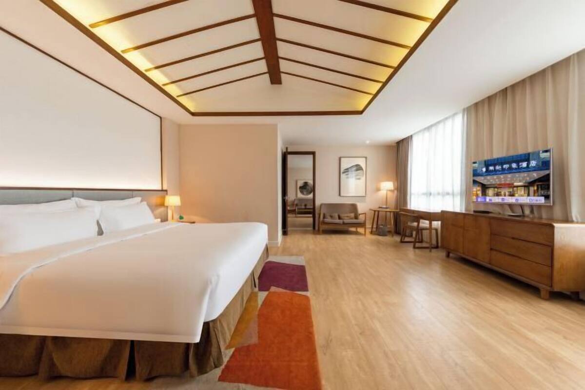 Ein Hotelzimmer mit Bett, Schreibtisch, Stuhl, Fernseher und einer Minibar.