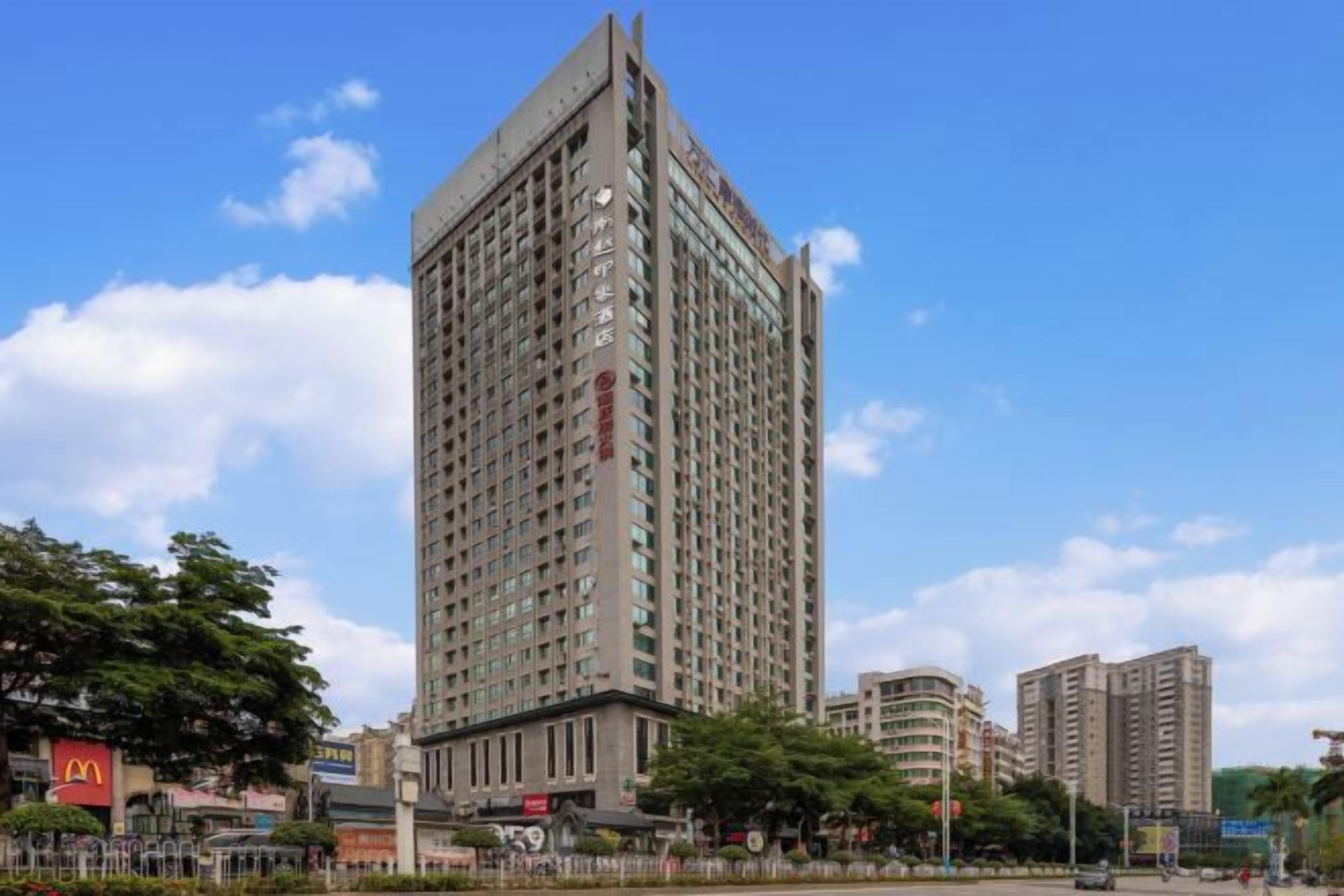 A high-rise building with multiple floors, surrounded by other buildings and trees.