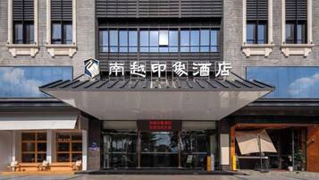 A hotel entrance with a modern facade, large windows, and a covered entrance area.