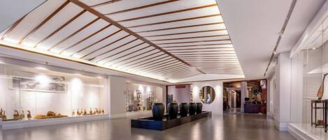A spacious lobby with a modern ceiling design, a reception desk, and a display of decorative items.