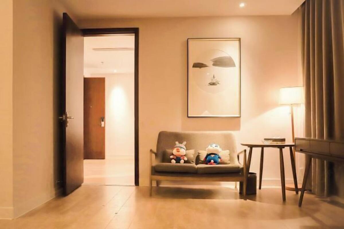 Ein Hotelzimmer mit einer Couch, einem kleinen Tisch, einer Lampe und einem gerahmten Kunstwerk an der Wand.