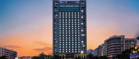 Un edificio de gran altura con diseño moderno, que presenta una cuadrícula de ventanas y un techo plano.