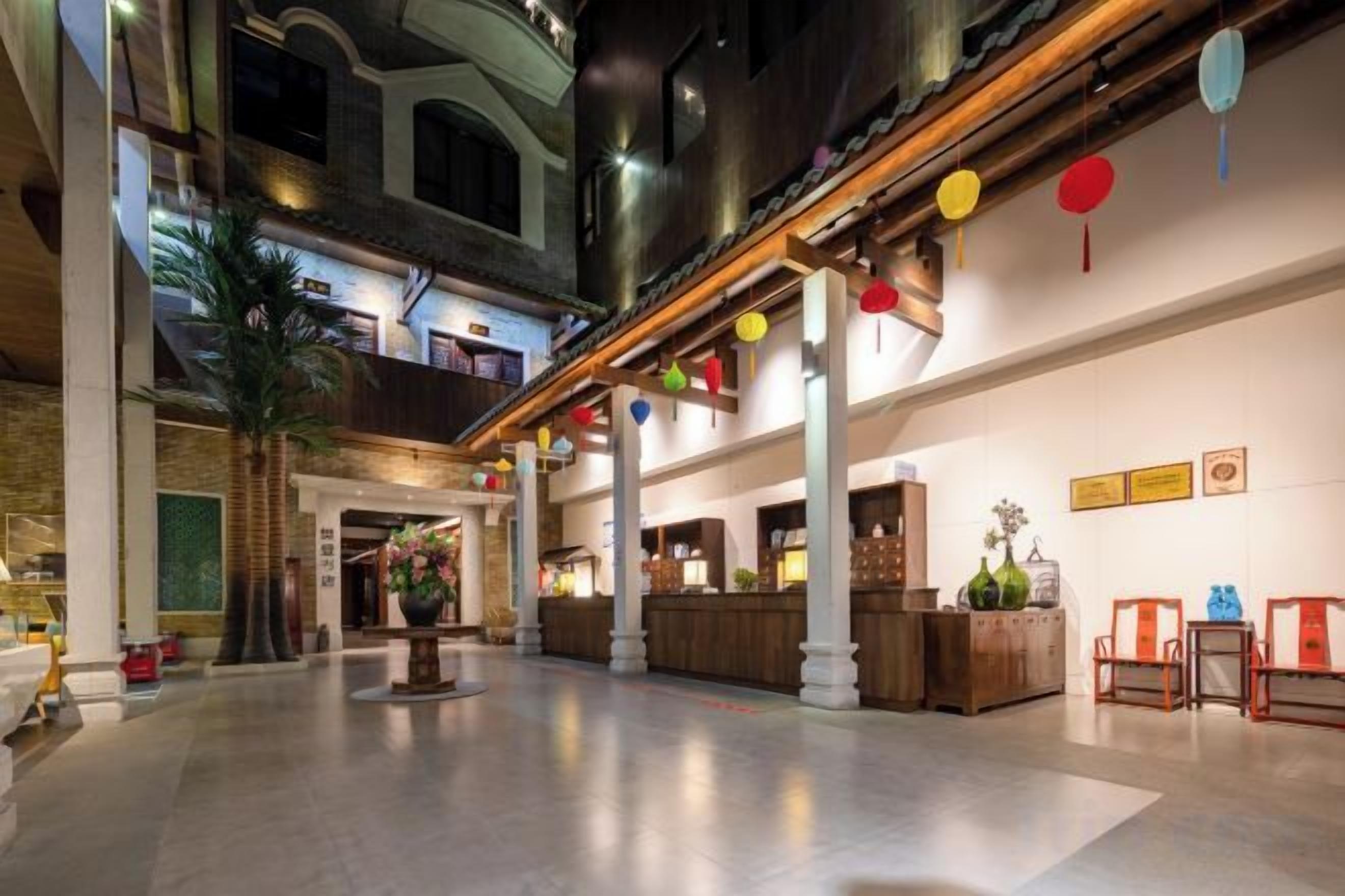 A spacious lobby with a high ceiling, a reception desk, and a large plant in the center.