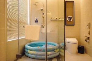 Un baño con cabina de ducha de vidrio, inodoro, lavabo y un cuadro en la pared.