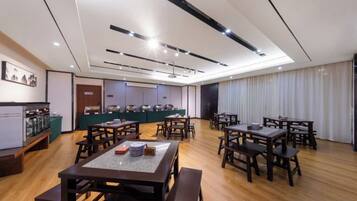 Un comedor amplio con varias mesas y sillas, una barra con exhibición de alimentos y una zona de cocina al fondo.