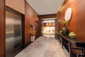 A hallway with a marble floor, wooden walls, a reception desk, and a door leading to a room. - Maoming Nanyue Impression Hotel (1959 Wenchuang Street High Speed Railway Station) (Maoming)