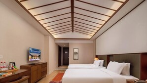 Habitación de hotel con dos camas, un escritorio, un televisor y un techo con vigas de madera.