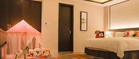 A bedroom with a bed, a door, a small table with toys, and a tent-like structure.