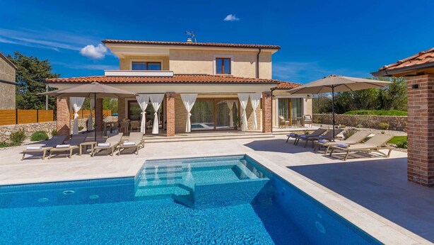 A two-story house with a swimming pool, outdoor seating, and a covered patio area.