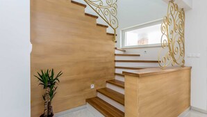 A wooden staircase with a glass window at the top, a potted plant, and a decorative metal railing.