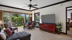 Un salon avec un canapé gris, un meuble de rangement rouge et un ventilateur de plafond.