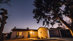 Uma casa térrea com garagem, cercada por um gramado bem cuidado e uma árvore grande.
