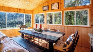 A wooden cabin with a dining table, chairs, and a sofa. - Gated Carmel Valley Retreat with 20 Acres, Pool & Hot Tub (Carmel Valley)