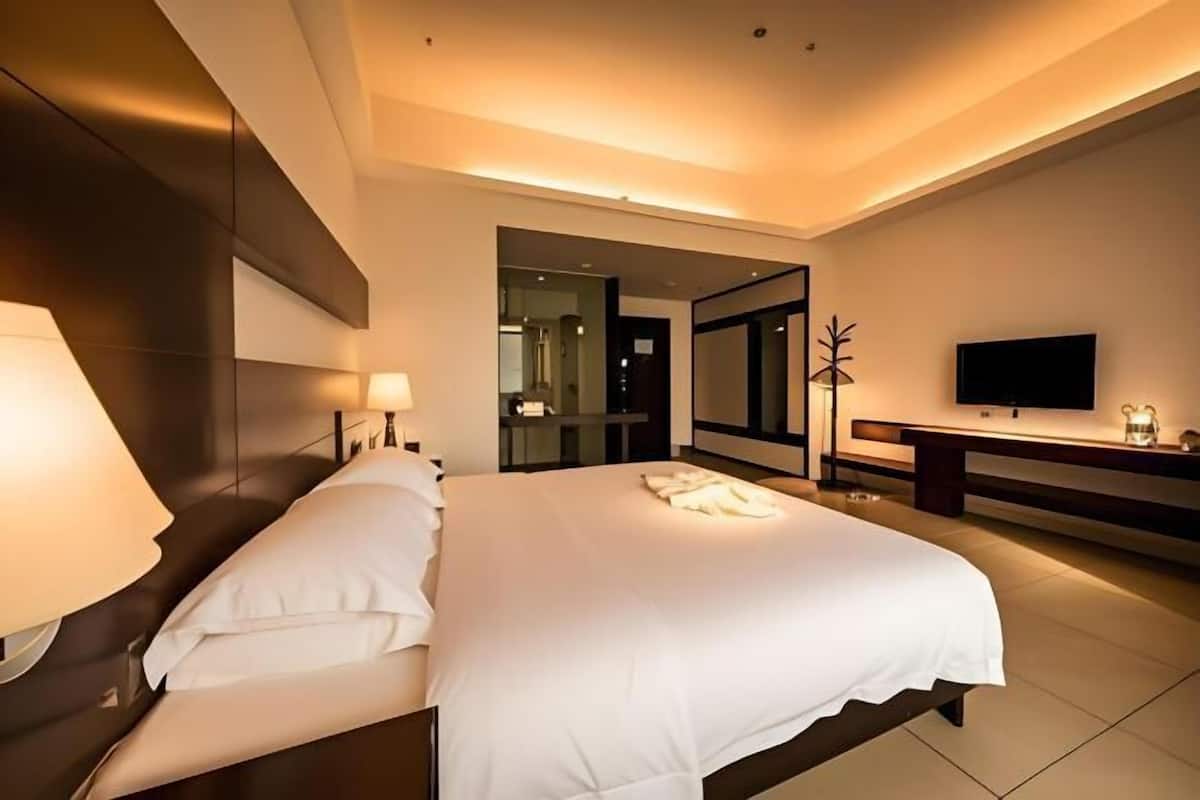 Ein modernes Hotelzimmer mit einem großen Bett, Nachttischlampen, einem Flachbildfernseher und einem Spiegel.