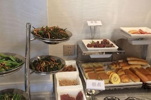 Un buffet proposant une variété de plats, notamment des légumes, des viandes et des pâtisseries.