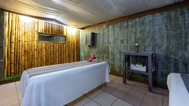 A room with a bed, a small table with towels, a mirror, and a wall with a bamboo panel. - Royal Club at Park Royal Beach Huatulco - Vacation Club (Santa María Huatulco)