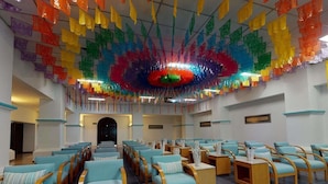 A hotel lobby with rows of teal chairs, wooden side tables, and a colorful ceiling decoration. - Royal Club at Park Royal Beach Huatulco - Vacation Club (Santa María Huatulco)