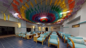 A spacious hall with rows of seating and a colorful ceiling decoration. - Royal Club at Park Royal Beach Huatulco - Vacation Club (Santa María Huatulco)