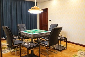Een hotelkamer met een eettafel, vier stoelen, een kroonluchter en een kamerbreed tapijt met dessin.