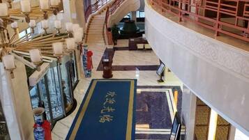 A hotel lobby with a blue carpet, a staircase, and traditional decor.
