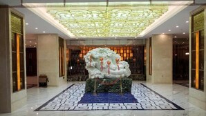 Un hall d’entrée doté d’un grand plafond orné, d’une sculpture décorative centrale et d’un sol à motifs.