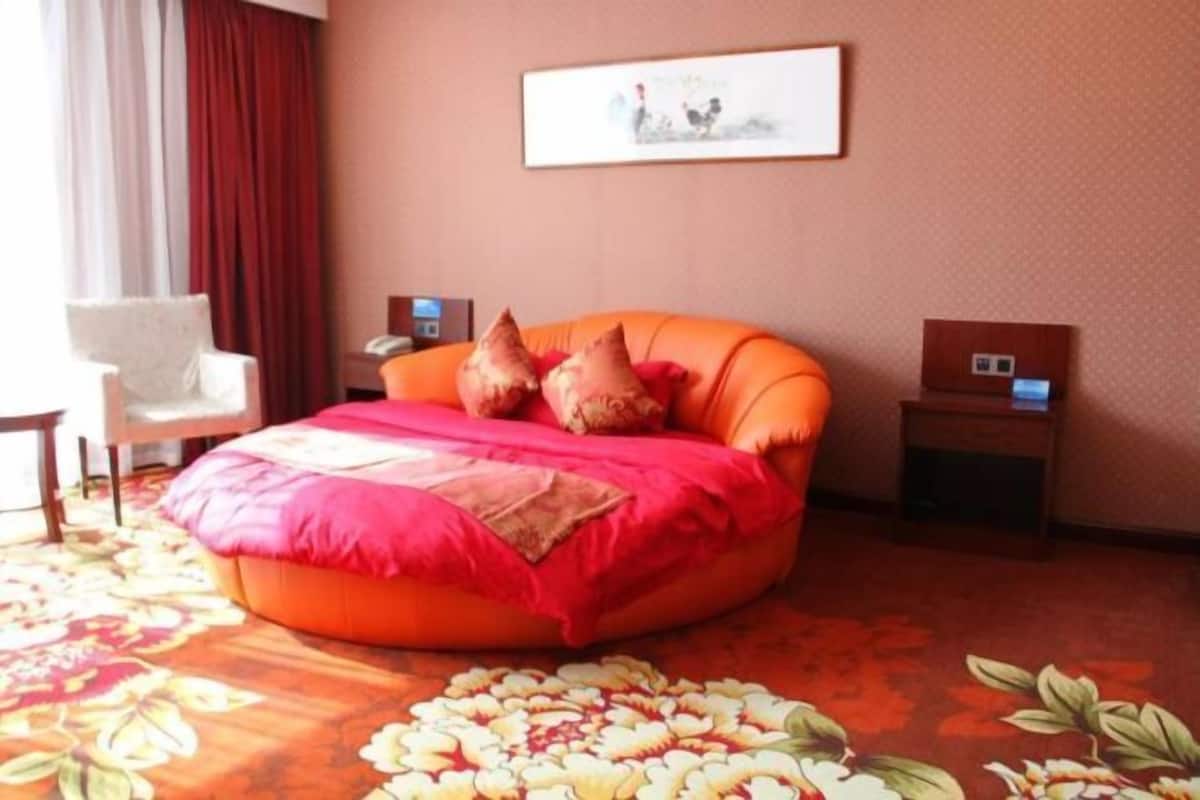 Une chambre à coucher comprenant un lit, une chaise, une table de chevet et une œuvre d’art accrochée au mur.