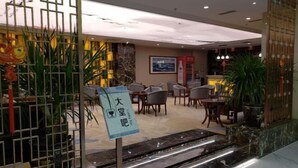 Un hall d’hôtel comprenant un comptoir d’accueil, un espace salon et un panneau indiquant l’emplacement d’un bar-salon.