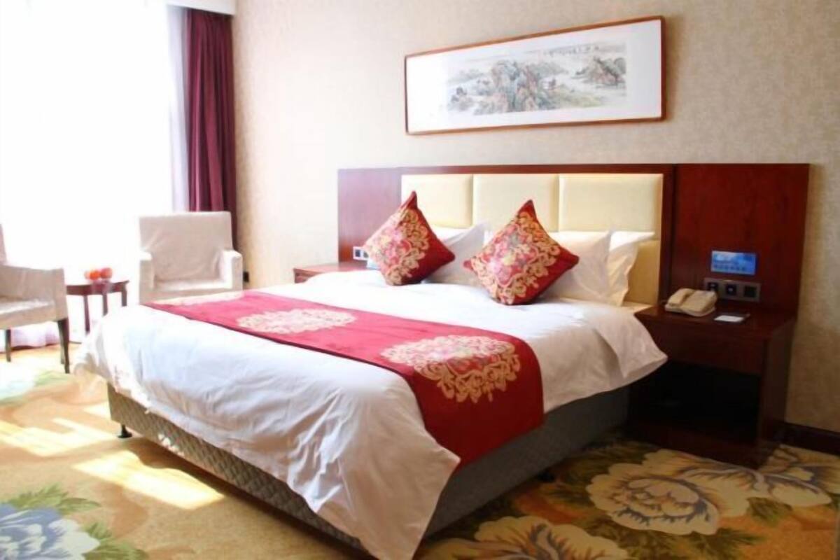 Une chambre d’hôtel avec un lit, une chaise, une table de chevet et un téléphone fixé au mur.