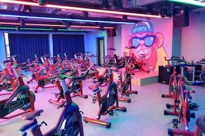 A gym with multiple stationary bikes arranged in rows.