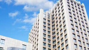 Un bâtiment avec une fontaine devant, une grande enseigne avec des caractères chinois et une structure imposante en arrière-plan.