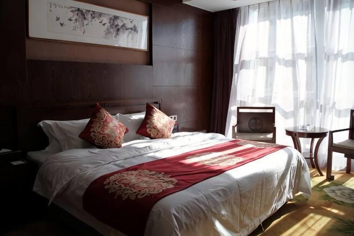 Une chambre d’hôtel avec un grand lit, une petite table, une chaise et une œuvre d’art encadrée au mur.