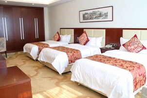 Habitación de hotel con tres camas, un escritorio y un armario grande.