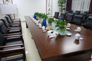 Un salón de conferencias con una mesa larga, sillas y una pizarra.